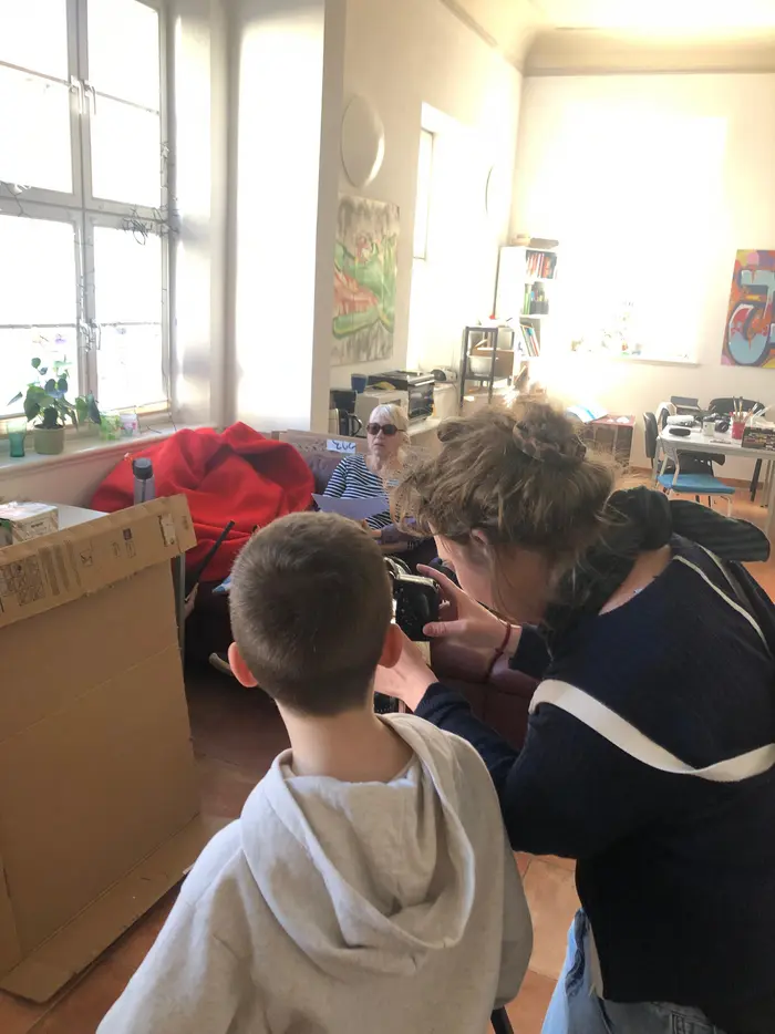 Ein Junge und eine Frau schauen durch ein Kameraobjektiv.